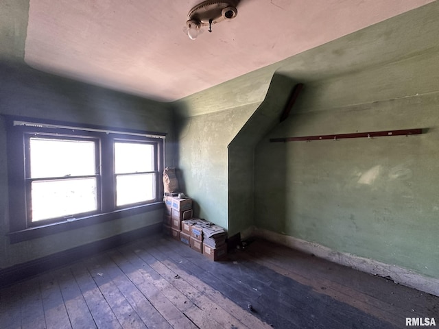 additional living space featuring baseboards and hardwood / wood-style floors