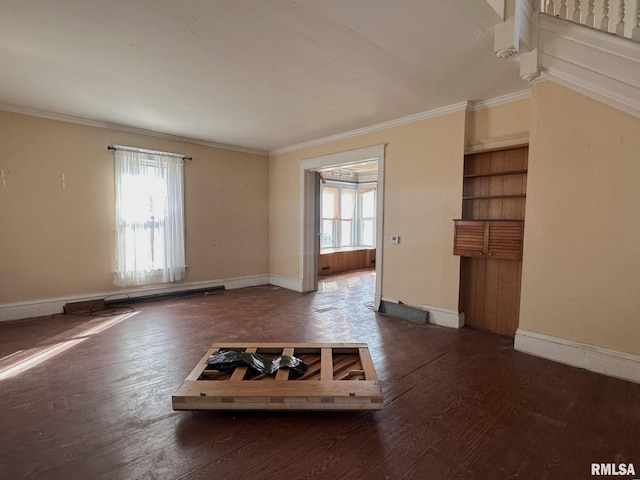 unfurnished living room featuring baseboards, wood finished floors, and crown molding