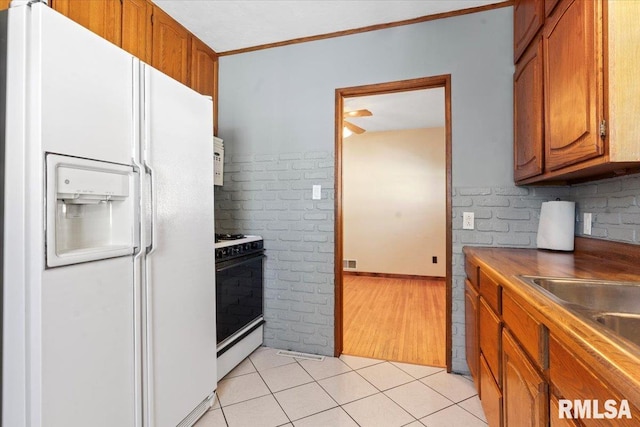 kitchen with visible vents, light tile patterned floors, brown cabinets, white appliances, and a sink