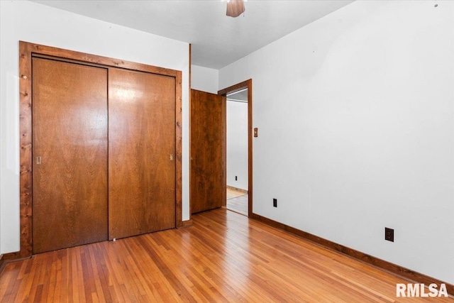 unfurnished bedroom featuring a closet, baseboards, hardwood / wood-style floors, and a ceiling fan