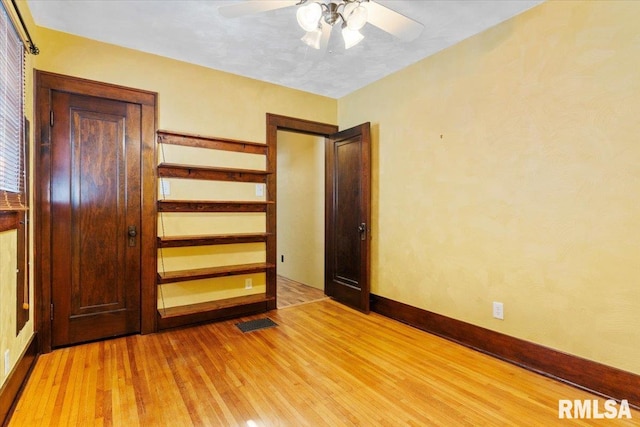 unfurnished bedroom featuring light wood-type flooring, visible vents, baseboards, and ceiling fan