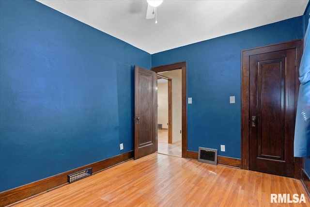 empty room with ceiling fan, wood finished floors, visible vents, and baseboards