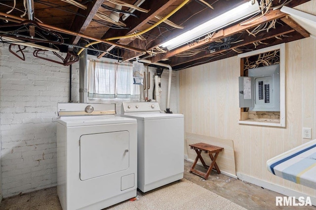 washroom with brick wall, wood walls, electric panel, laundry area, and separate washer and dryer