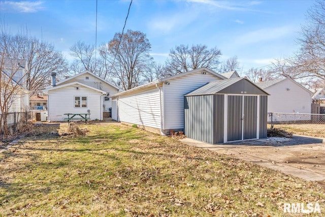 rear view of property featuring a yard, an outdoor structure, and fence