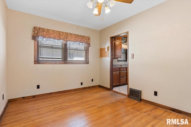 spare room with a ceiling fan, baseboards, visible vents, and light wood finished floors