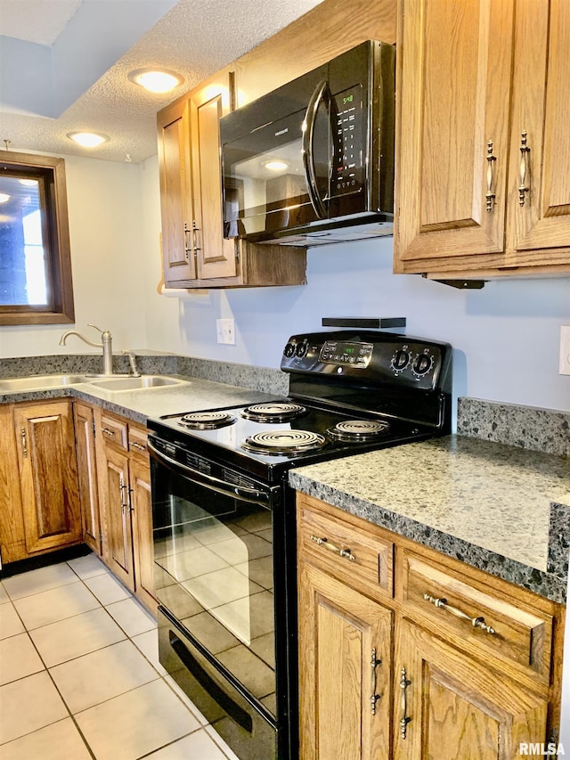 kitchen with a sink, black appliances, light tile patterned floors, and a textured ceiling