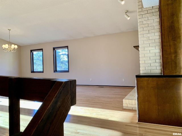 living area featuring a chandelier, light wood-type flooring, and vaulted ceiling