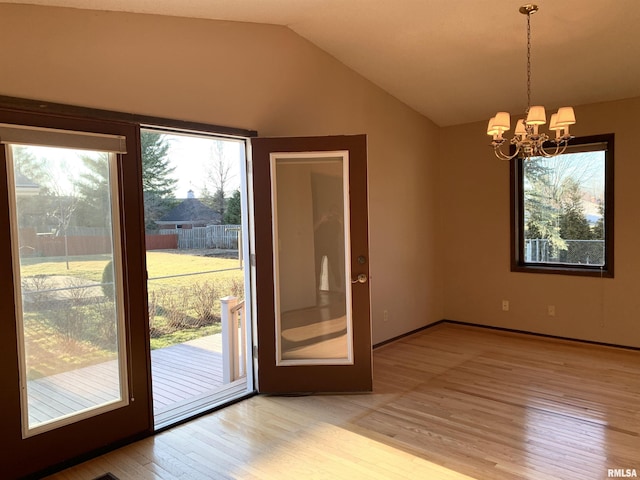 interior space featuring lofted ceiling, light wood-style floors, and an inviting chandelier