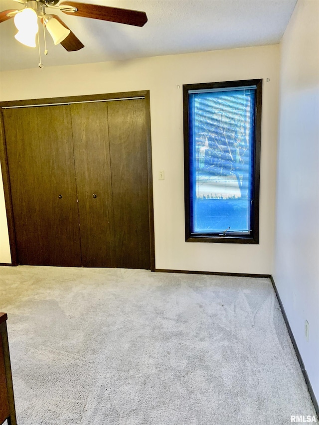 unfurnished bedroom with a ceiling fan, carpet, a closet, and baseboards