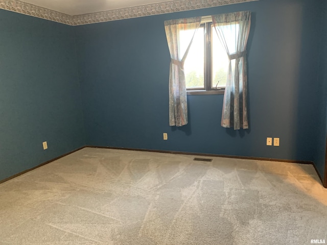 carpeted spare room with visible vents and baseboards