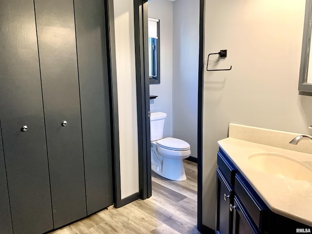 bathroom with toilet, wood finished floors, and vanity