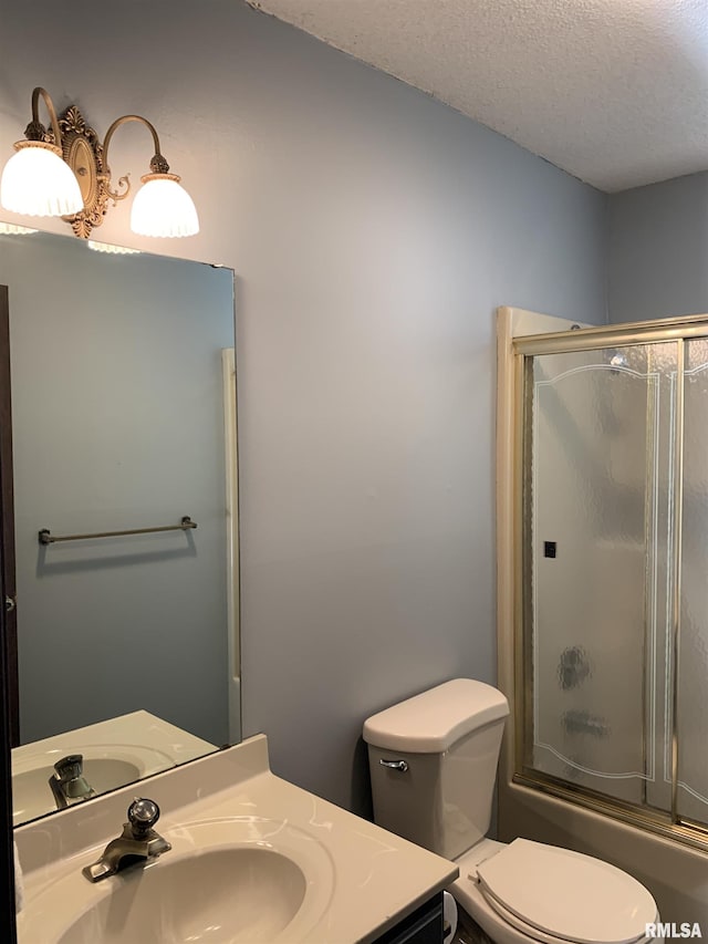 full bath featuring enclosed tub / shower combo, toilet, a textured ceiling, and vanity