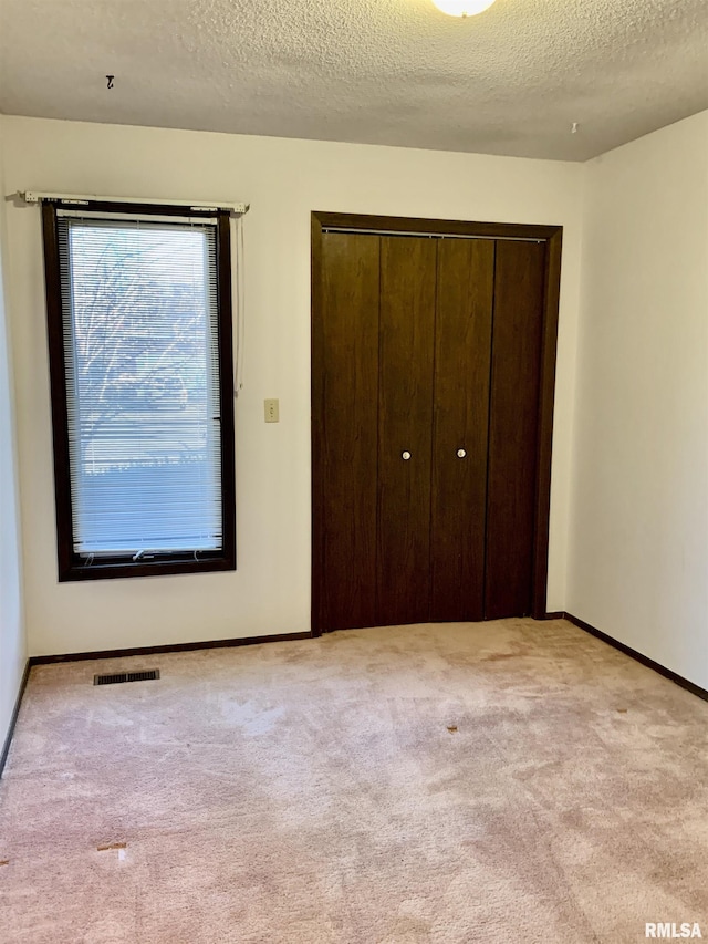 unfurnished bedroom featuring a closet, visible vents, baseboards, and carpet floors