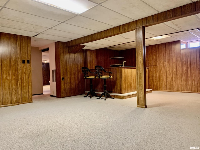 below grade area with carpet flooring, wood walls, and a dry bar