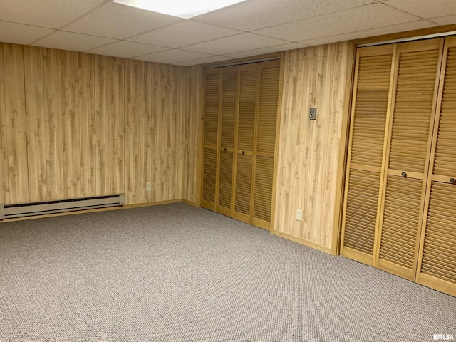 interior space featuring a baseboard radiator, wooden walls, and carpet flooring