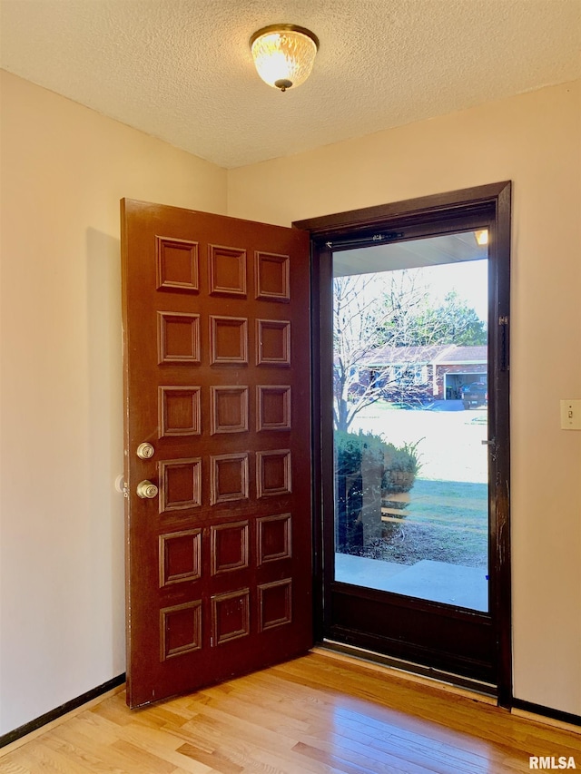 entryway featuring a textured ceiling, light wood-type flooring, and baseboards