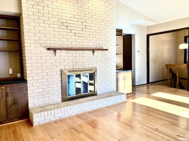 living area with wood finished floors, a fireplace, and vaulted ceiling