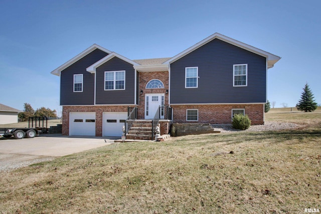 split foyer home with a front yard, brick siding, an attached garage, and driveway