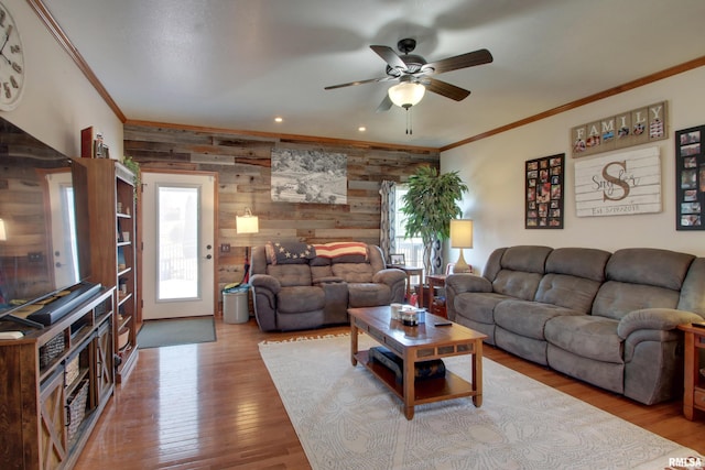 living room featuring a ceiling fan, crown molding, wood finished floors, and wood walls