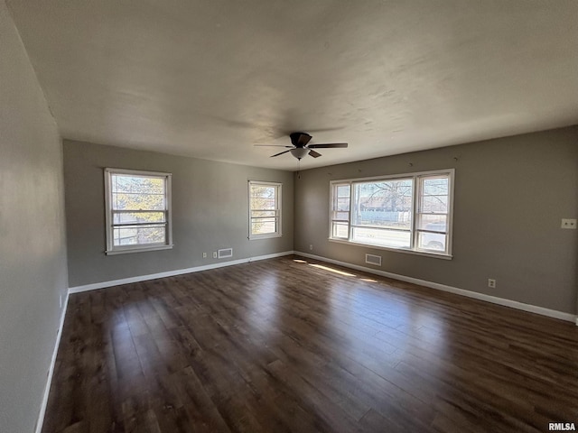 empty room with visible vents, dark wood-type flooring, and baseboards