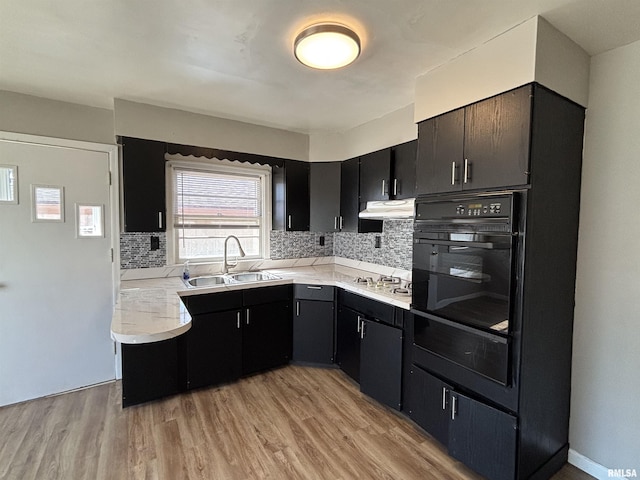 kitchen with oven, stainless steel gas stovetop, light countertops, and a sink