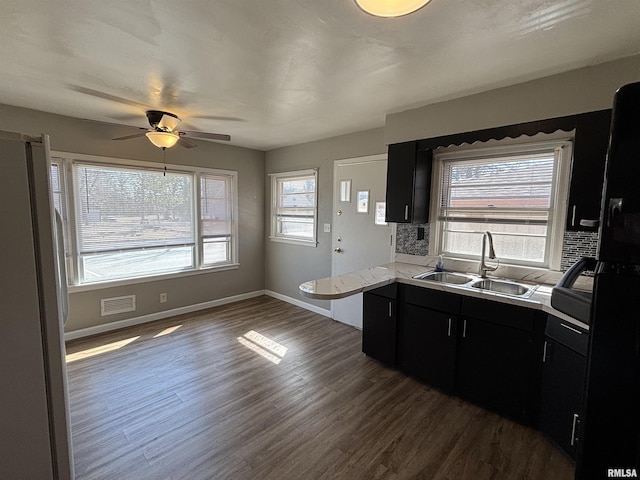 kitchen with dark wood-type flooring, a sink, freestanding refrigerator, light countertops, and dark cabinets