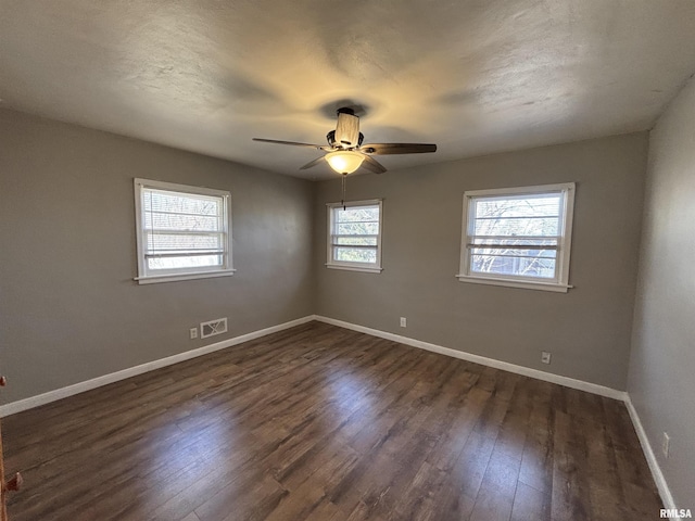 empty room featuring visible vents, baseboards, dark wood-style flooring, ceiling fan, and a textured ceiling