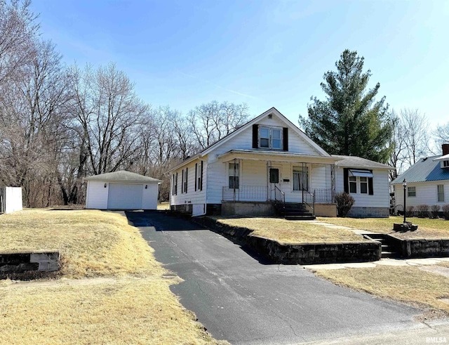 view of front of home with a detached garage, a front lawn, covered porch, an outdoor structure, and driveway