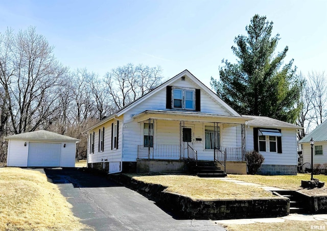 view of front of home featuring an outbuilding, aphalt driveway, a detached garage, a porch, and a front yard