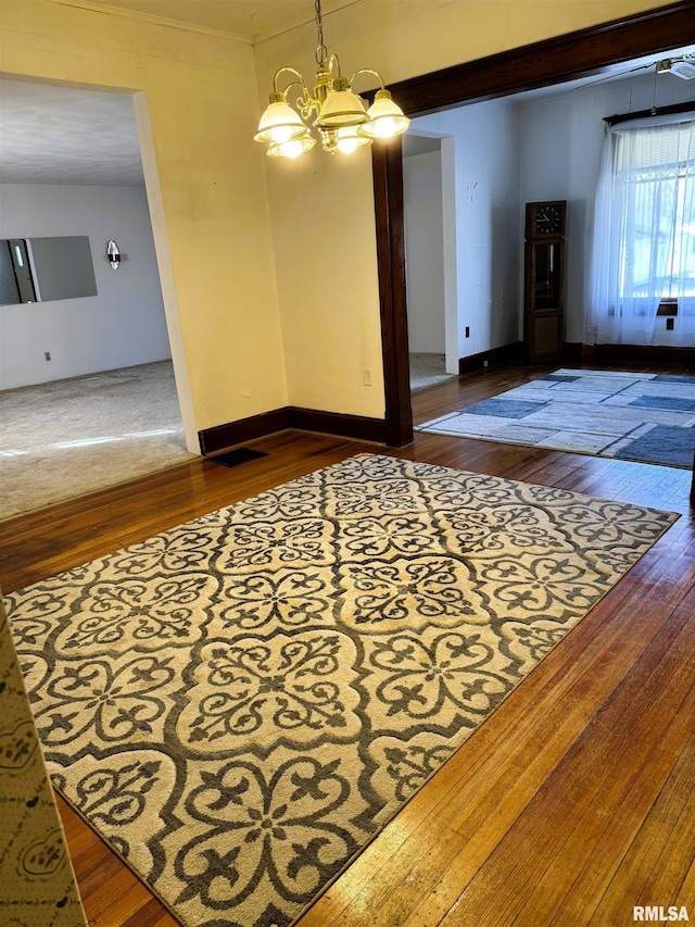 interior space with baseboards, wood-type flooring, and a notable chandelier