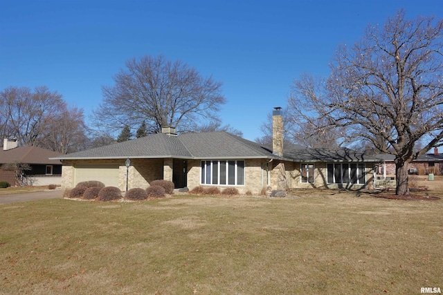 view of front of house featuring a front yard, roof with shingles, an attached garage, a chimney, and brick siding