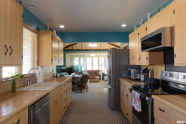 kitchen featuring a sink, stainless steel appliances, plenty of natural light, and decorative backsplash