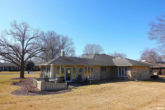 back of house with a lawn, roof with shingles, and a chimney