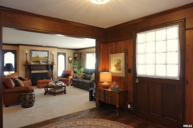 living area featuring a glass covered fireplace, crown molding, and wooden walls