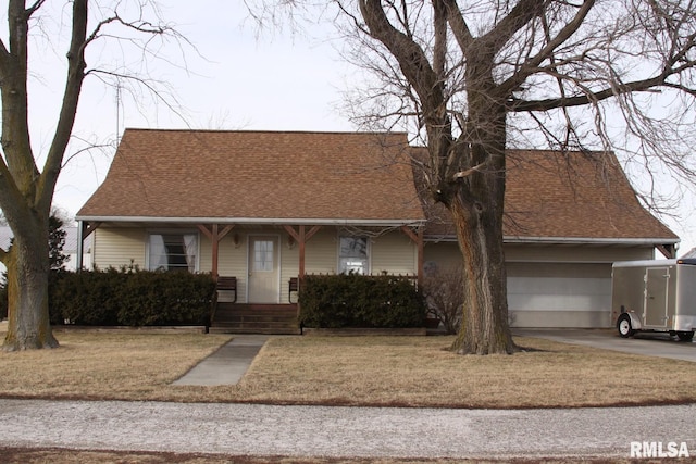 view of front of home with a front yard, roof with shingles, covered porch, and driveway