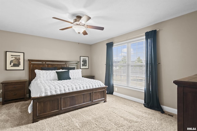 bedroom with visible vents, baseboards, light carpet, and a ceiling fan