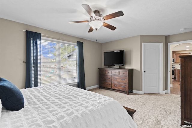 bedroom with arched walkways, ceiling fan, light carpet, and baseboards