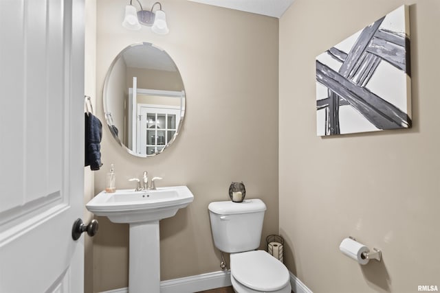 half bathroom with toilet and baseboards