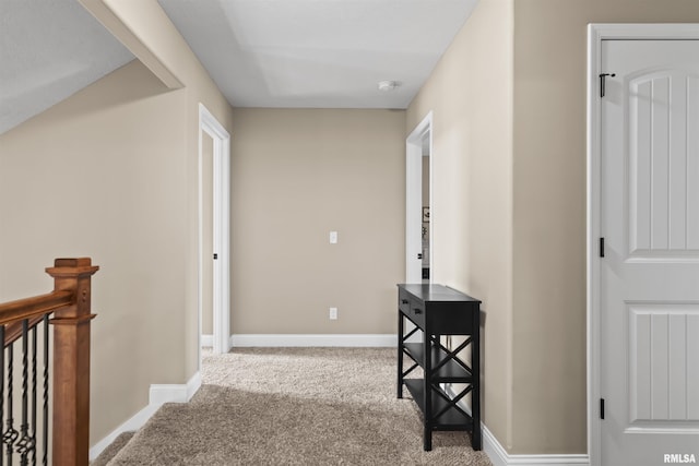 corridor with baseboards, an upstairs landing, and carpet flooring