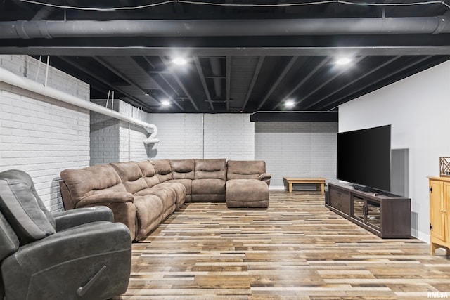 living area featuring wood finished floors and brick wall