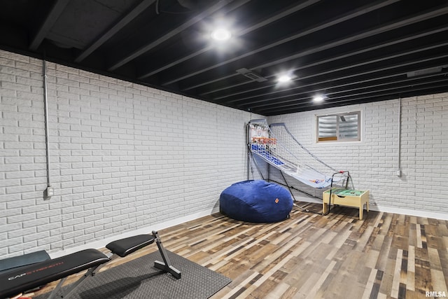 exercise area with wood finished floors and brick wall