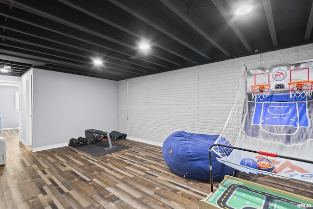 interior space featuring wood finished floors, baseboards, and brick wall