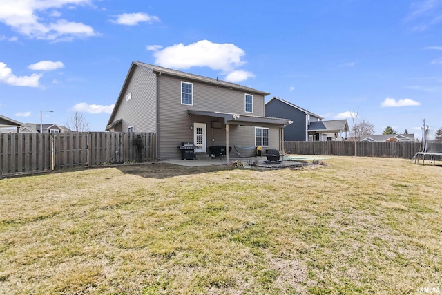 back of property with a yard, a trampoline, a fenced backyard, and a patio area