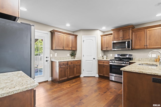 kitchen featuring a sink, dark wood-type flooring, light stone counters, and stainless steel appliances