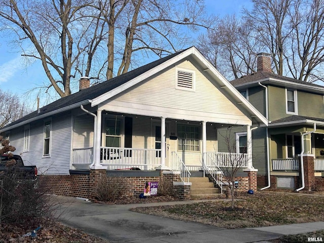 view of front facade featuring covered porch and a chimney