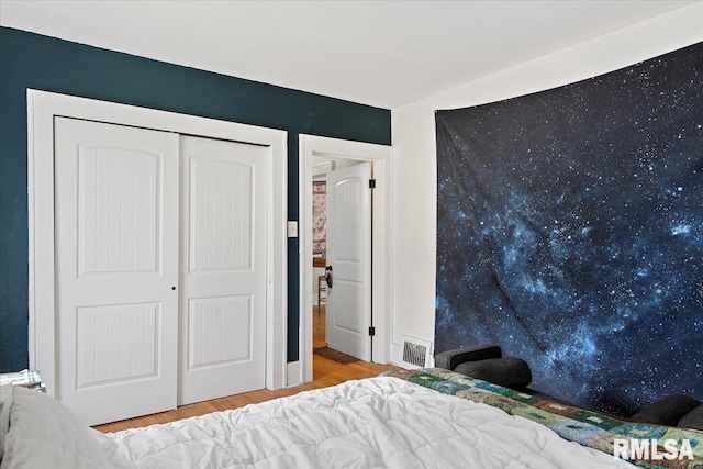 unfurnished bedroom featuring visible vents, a closet, and wood finished floors