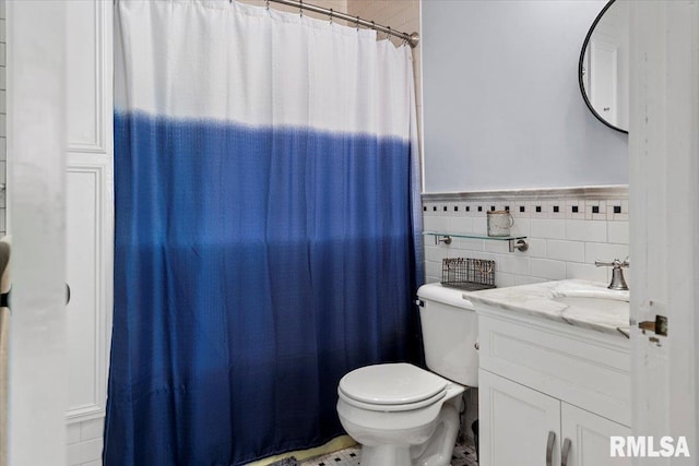 full bathroom featuring toilet, curtained shower, tile walls, wainscoting, and vanity