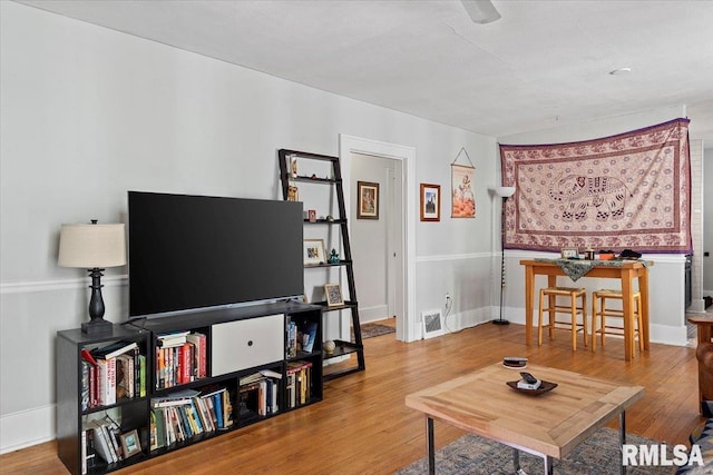 living area featuring visible vents, baseboards, and wood finished floors