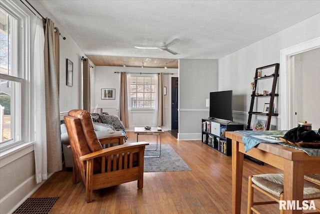 living room featuring hardwood / wood-style floors, baseboards, visible vents, and ceiling fan