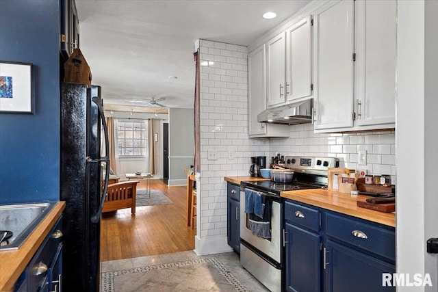 kitchen featuring blue cabinetry, black appliances, white cabinets, under cabinet range hood, and wood counters